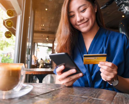 Woman holds a credit card and a phone in a resturant.