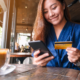 Woman holds a credit card and a phone in a resturant.