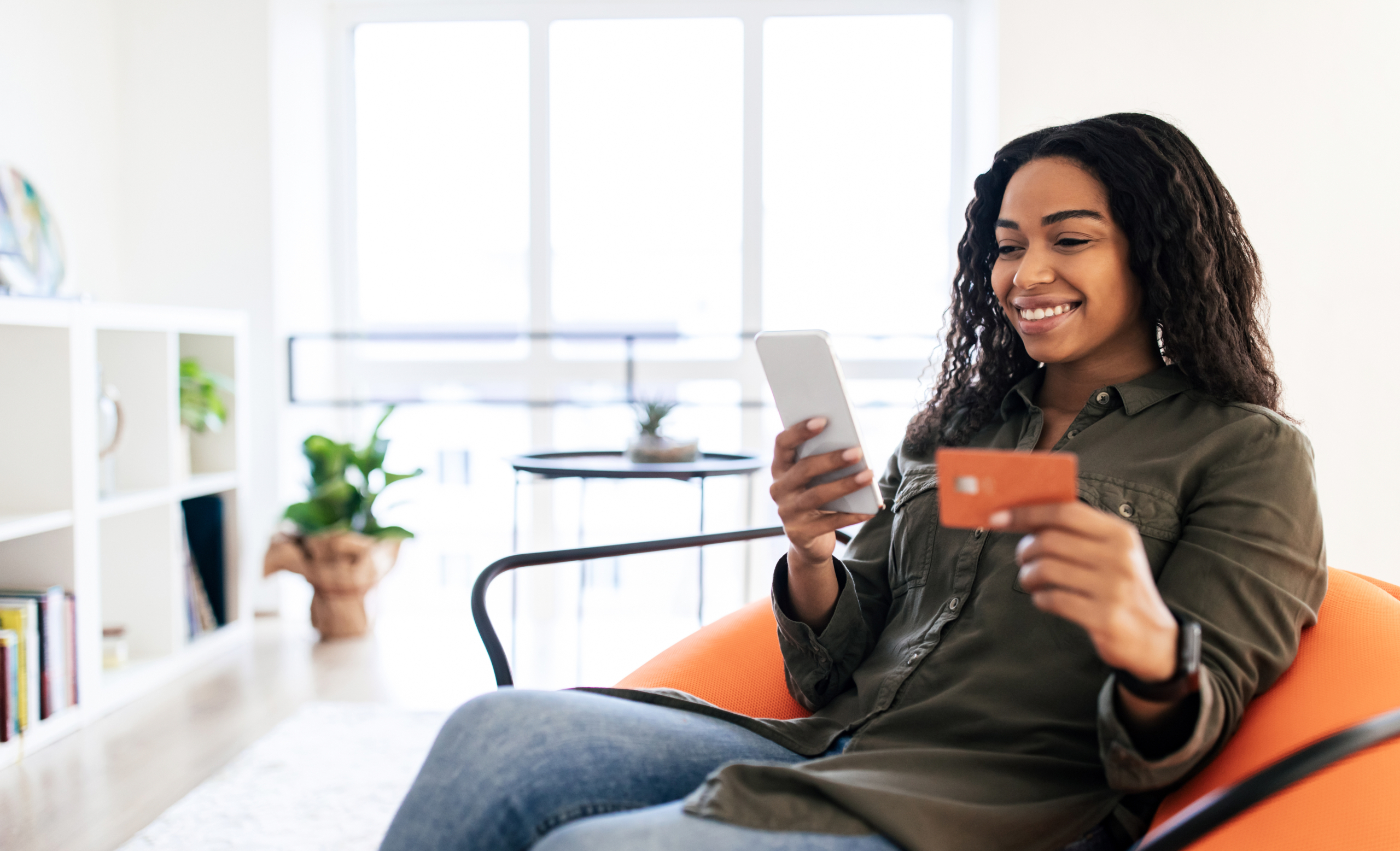 Smiling business owner holding a Bank St. Croix business credit card in an office setting.