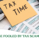 Calculator and tax forms with a sticky note on top with the words Tax Time.