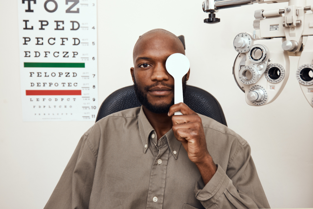 HSA-Vision-Care-Savings-Eye-Exam-Preventative Man receiving an eye exam next to a vision chart, representing vision care costs covered by a Health Savings Account (HSA).