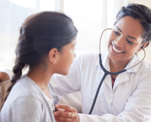 Smiling doctor using a stethoscope to examine a young patient, symbolizing future healthcare and HSA savings.