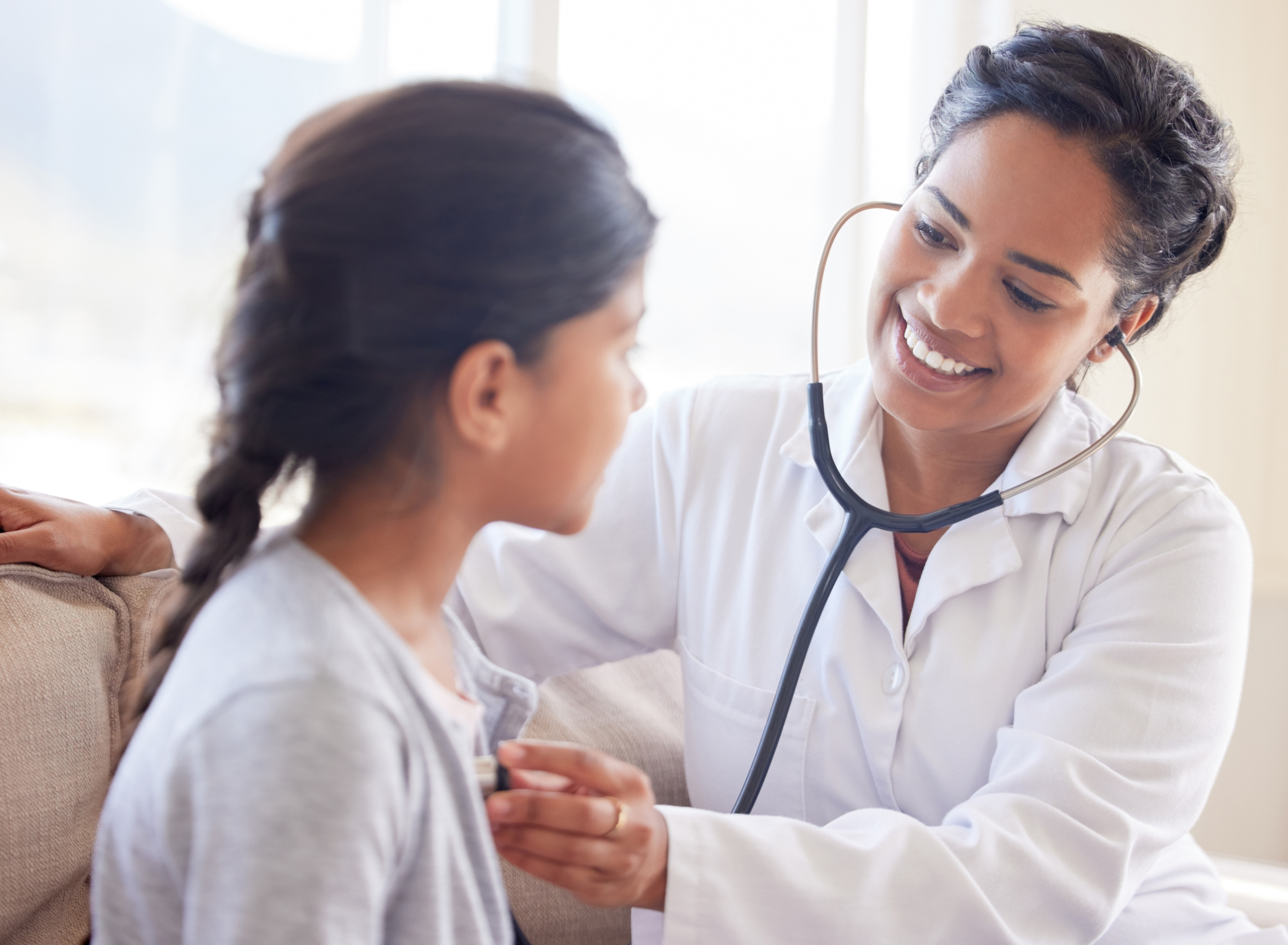 Smiling doctor using a stethoscope to examine a young patient, symbolizing future healthcare and HSA savings.
