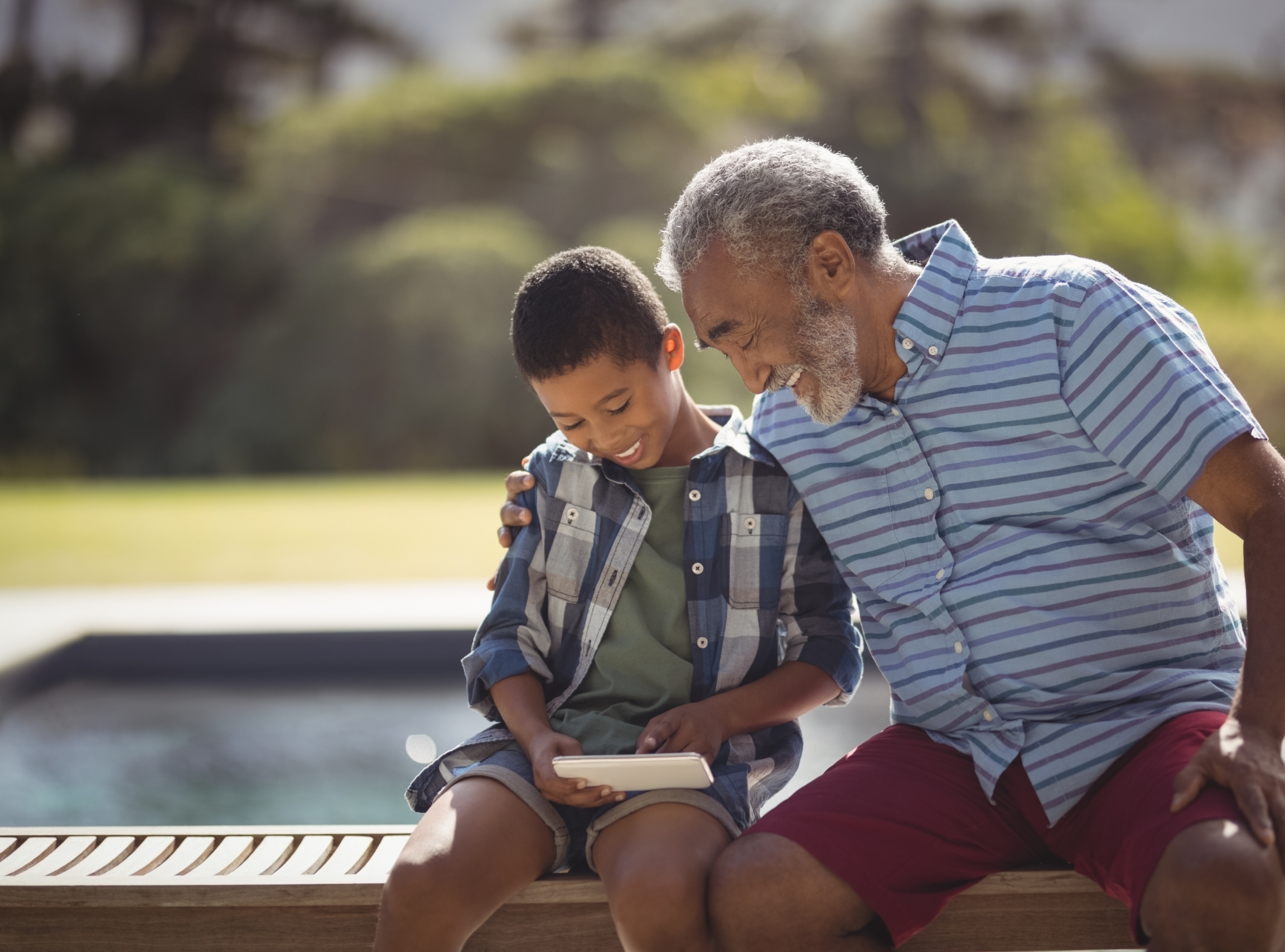 Grandfather and grandson planning their financial future together on a tablet, symbolizing the security of a long-term Certificate of Deposit.