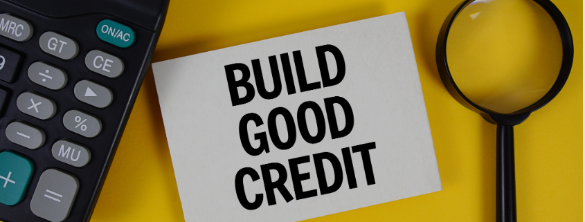 Calculator, magnifying glass and a sign that reads Build Good Credit.