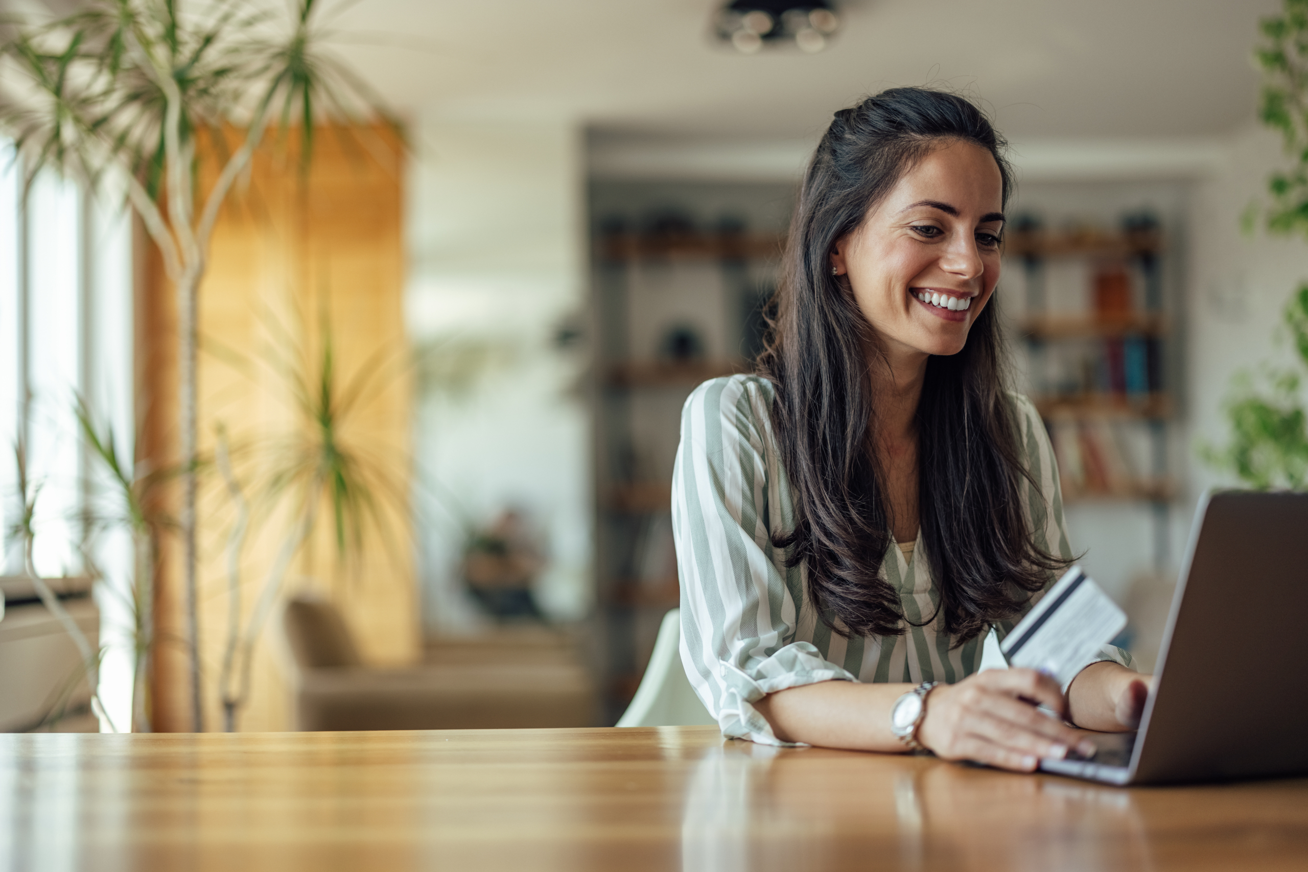 Joyful adult woman, checking her bank account, online, at home