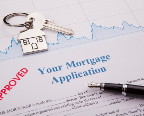 House key on a silver house keychain and a pen laying on top of an approved mortgage application from Bank of St. Croix.
